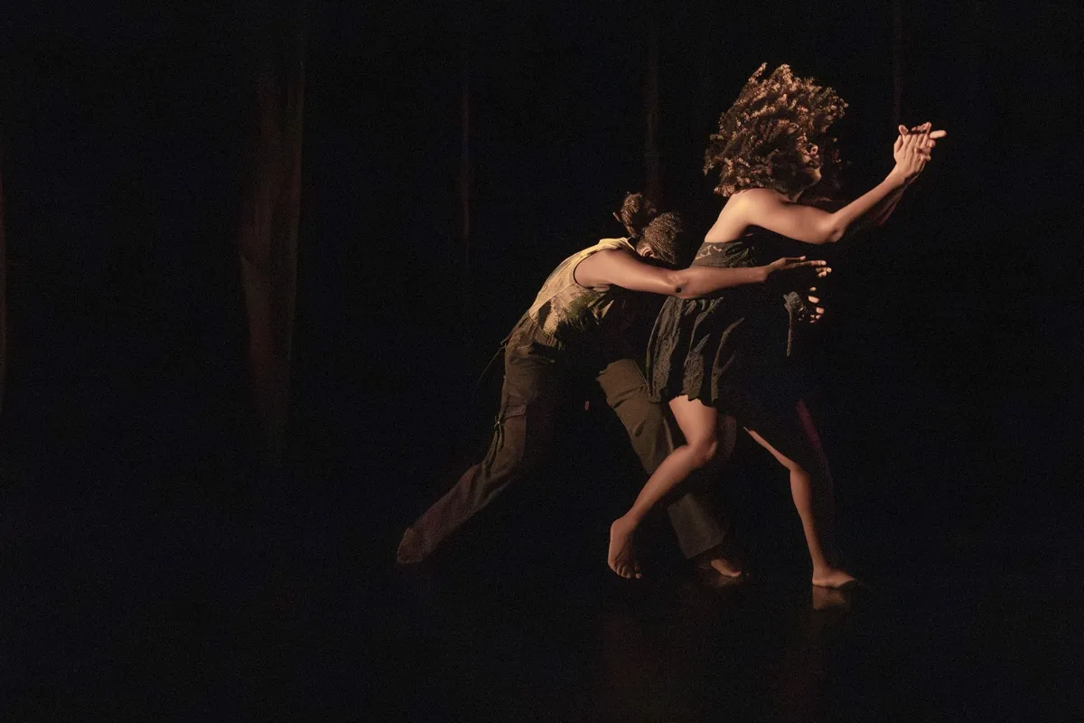 Two dancers lean into an intimate embrace under warm stage lighting.